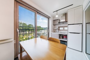 A modern kitchen with a dining table, a built-in oven, and a view of the outdoors. - Samcheok The Ggeullim Pension (Samcheok)