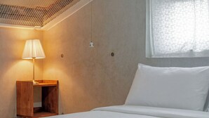 A bedroom with a bed, a nightstand, a lamp, and a window with a view.