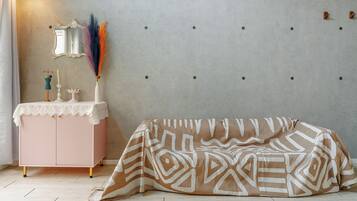 Una habitación con un armario rosa, un espejo, adornos y una manta estampada en el suelo.