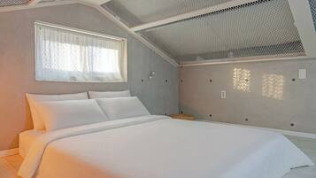 Un dormitorio con cama, una ventana con cortinas traslúcidas y un techo inclinado con diseño de malla.