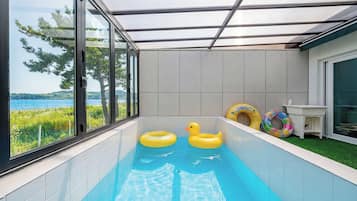 Una piscina con vistas al mar, rodeada por un recinto de cristal.