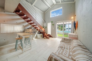 Un espacio habitable compacto con una escalera de madera, una zona de comedor, un sofá y vistas a una piscina.