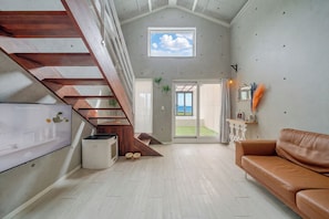 A modern interior with a wooden staircase, a sofa, and a view of the outdoors. - Taean Badameong Pet Pool Villa (Taean)