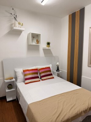 A bedroom with a large bed, white walls, and a striped curtain. - APARTMENT in Cali Tequendama-Ideal for rest and recuperation (Cali)