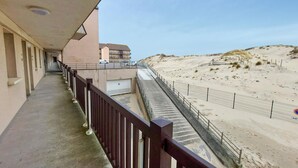 A balcony with a view of a sandy beach and a building in the background. - Bel appartement vue mer (Camiers)