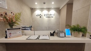 Ein Empfangsschalter mit einem Schild, auf dem 'YUNDAM STAY' steht, und der Möglichkeit zum kontaktlosen Check-in.