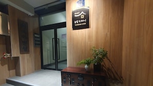Ein Empfangsschalter mit Holzoptik, ein Schild mit der Aufschrift 'Yundam Stay' und ein Blumentopf auf dem Schalter.