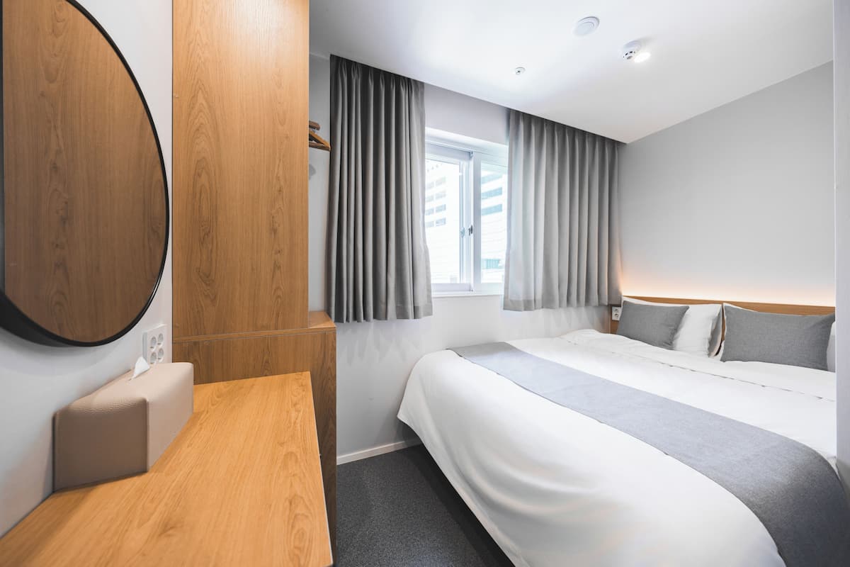 Una habitación de hotel moderna con cama, mesita de noche y un espejo grande.