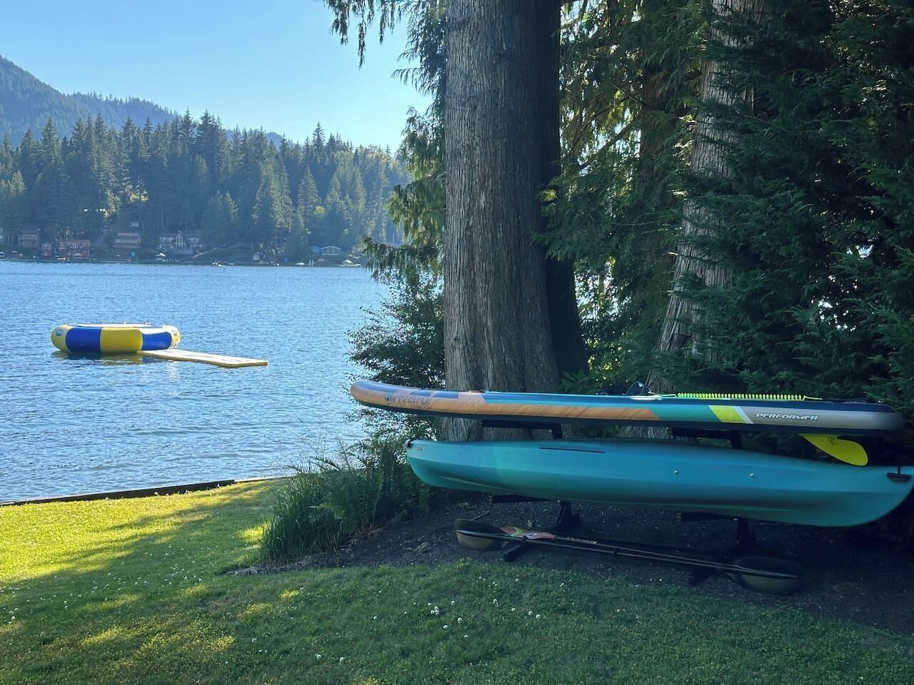 Un paisaje junto al lago con kayaks y una tabla de remo.