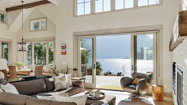 Ein geräumiges Wohnzimmer mit einem großen Schiebeglastür, die auf einen Balkon mit Meerblick führt. Es gibt ein Sofa, einen Couchtisch und einen Sessel.