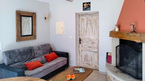 A living room with a sofa, a coffee table, a fireplace, and a door. - Pet friendly home in Monieux (Monieux)
