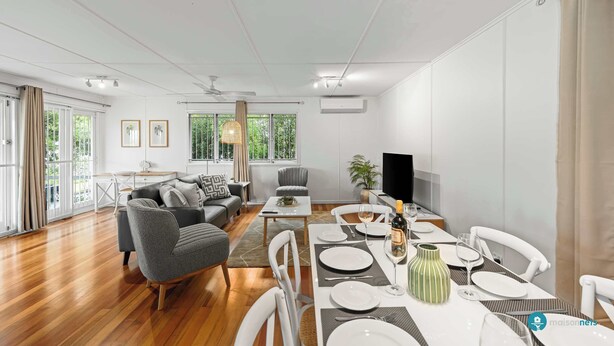 Una sala de estar moderna con comedor, ventanas amplias y televisor de pantalla plana.