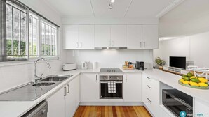 Una cocina moderna con armarios blancos, electrodomésticos de acero inoxidable y suelo de madera.