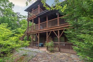 A two-story wooden cabin with a balcony, surrounded by dense forest. - Firefly Lodge - Cabin w Mountain Views & Fire pit (Black Mountain)