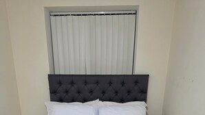 A bed with a tufted headboard, white bedding, and a grey furry throw blanket. - Modern 1-Bed Penthouse — Steps from Old Trafford (Stretford)