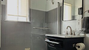 Un baño con ducha de vidrio, bañera, lavabo con encimera de mármol y retrete.