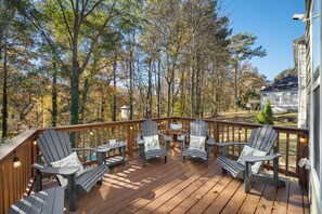 A wooden deck with Adirondack chairs and a table, surrounded by trees. - Beautiful Modern Home! Quiet Relaxing Convenience! (Atlanta)