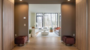 A modern living room with a sofa, a chair, and a coffee table. There are two ottomans and a rug on the floor. - New! The Woods ;  Luxury Home, Pool,  Hot Tub, Fire pit (Saugerties)
