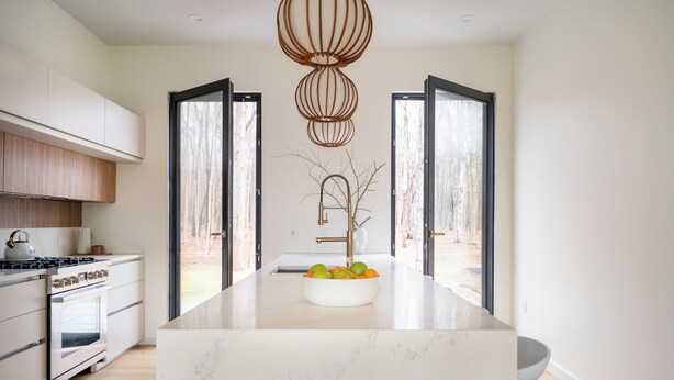 A modern kitchen with a marble island, built-in oven, and a large window. - New! The Woods ;  Luxury Home, Pool,  Hot Tub, Fire pit (Saugerties)