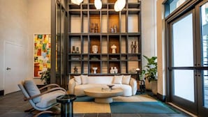 Un salon moderne avec un canapé d’angle, une table basse et une bibliothèque remplie d’objets décoratifs.