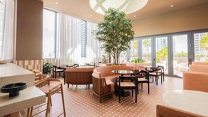 Un espace intérieur moderne, agrémenté d’un arbre central, de tables rondes et de sièges confortables.