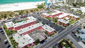 Una vista aerea di una zona alberghiera sulla costa, con diversi edifici, una spiaggia e un parcheggio.