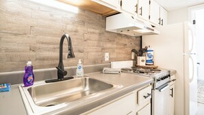 Una cocina con un lavamanos de acero inoxidable, una estufa y armarios blancos.