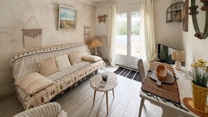 Een gezellige woonkamer met een gestreept sofa, een klein rond tafeltje en een televisie.