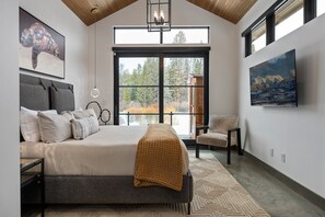 Ein Schlafzimmer mit einem großen Bett, Blick ins Freie und Bildern an den Wänden.