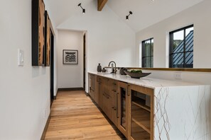 Eine moderne Küche mit Holzausstattung, einer Marmorarbeitsplatte und einem großen Fenster.