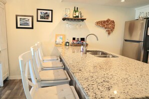 A kitchen with a granite countertop, stainless steel sink, and a refrigerator. - 3-bedroom town home on the water with a pool, fishing pier, boat ramp!!!! (Rockport)