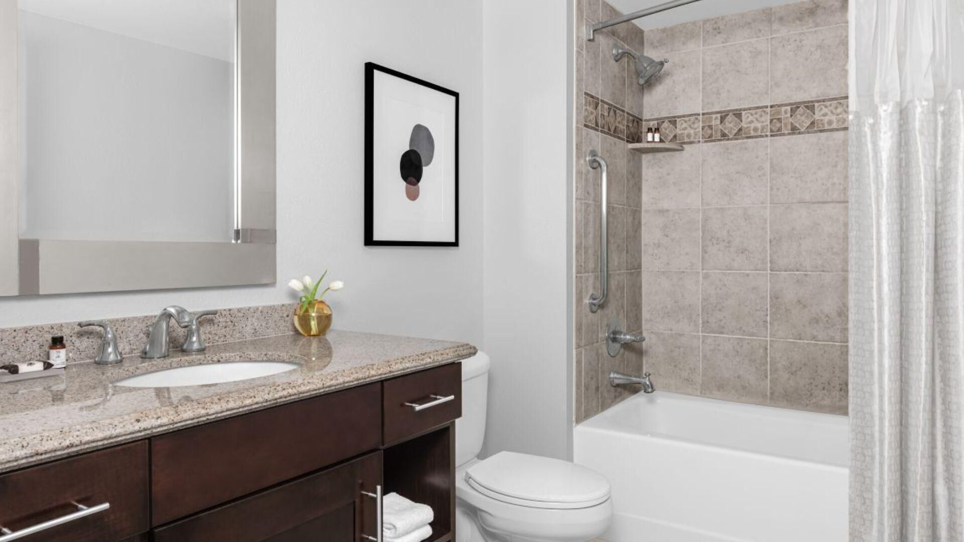 A modern bathroom with a sink, mirror, toilet, and shower.