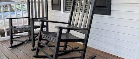 A porch with two rocking chairs and a small table.