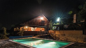 Una casa moderna con piscina, fachada de madera y chimenea de piedra.