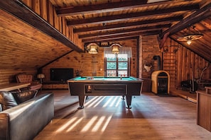 Een gezellige kamer met een pooltafel, een leren bank en een open haard.