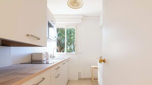 Una cocina moderna con encimera de madera, electrodomésticos integrados y ventana con vistas a zonas verdes.