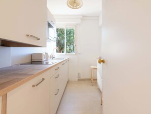 Eine moderne Küche mit Holz Arbeitsplatte, integrierten Geräten und einem Fenster mit Blick auf Grünflächen.