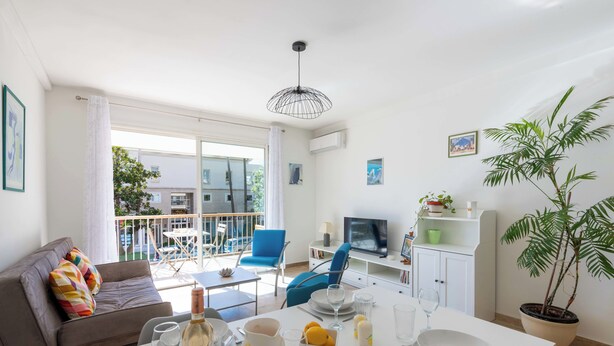 Una sala de estar moderna con comedor, sofá, televisor y balcón con vistas a la ciudad.