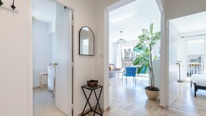 Un pasillo espacioso con diseño moderno que conduce a un área de comedor con una planta grande en maceta y una silla azul.