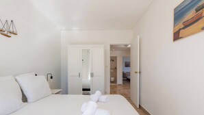 Habitación de hotel con una cama grande, un armario y un baño visible a través de una puerta abierta.