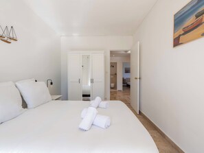 Ein Hotelzimmer mit einem großen Bett, einem Schrank und einem durchgegangenen Tür angedeuteten Badezimmer.
