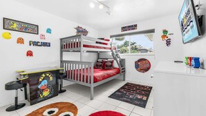 Quarto de criança com cama beliche, jogos de fliperama e diversos itens colecionáveis de jogos.
