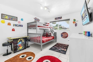 A child's room with a bunk bed, arcade games, and various gaming memorabilia. - WATERFRONT - Walk to Beach, Pool/Spa, Kayaks, Bikes, Direct Gulf Access - Retro Retreat - Roelens (Cape Coral)