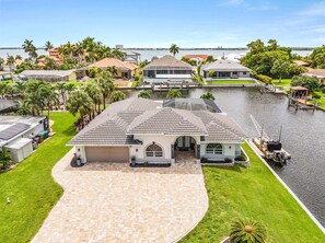 A waterfront property with a large house, a dock, and a boat. - WATERFRONT - Walk to Beach, Pool/Spa, Kayaks, Bikes, Direct Gulf Access - Retro Retreat - Roelens (Cape Coral)