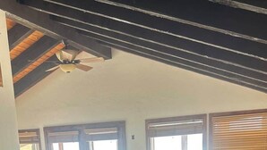Un dormitorio con cama, ventilador de techo y ventanas amplias.