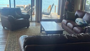 Una sala de estar con un sofá de cuero, una mesa de centro y vistas a un lago a través de amplios ventanales.