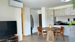 Una sala de estar moderna con televisor, mesa de comedor y sillas.