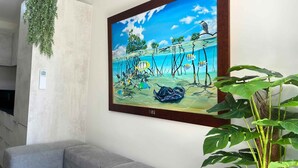 Una pintura de una escena submarina tropical con peces y un pájaro en una rama, enmarcada y colgada en una pared.