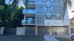 Un edificio moderno con un letrero de Tropical Living, que presenta patrones geométricos y un balcón.