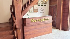 Un mostrador de recepción con un cartel que dice 'Reception' y una escalera que sube a un piso superior.